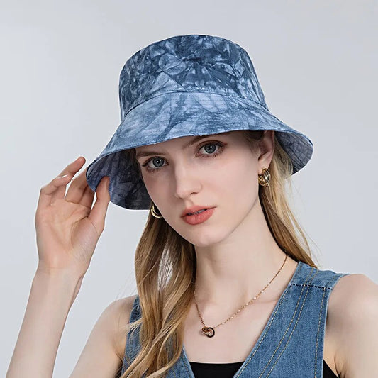 Tie Dye Bucket Hat on model in blue front view with her hand on hat